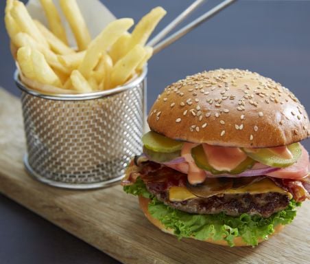 A burger and fries on a wooden plank